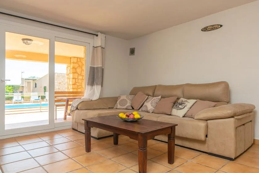 A living room with beige seating and a wooden coffee table beside sliding glass doors.