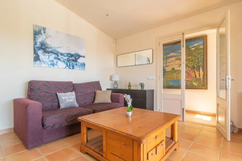 A living room with a sofa, wooden coffee table, and colorful wall art.