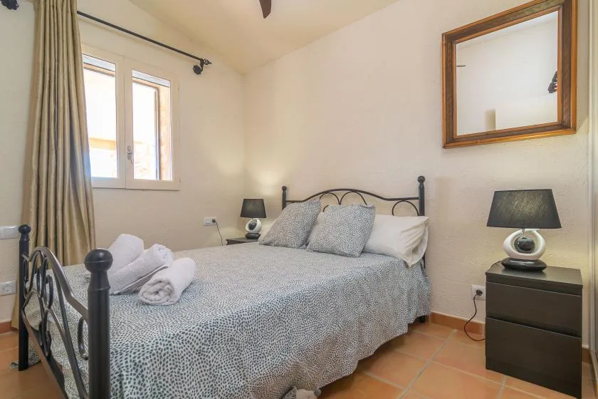 A bedroom with a double bed, bedside tables, and a window.
