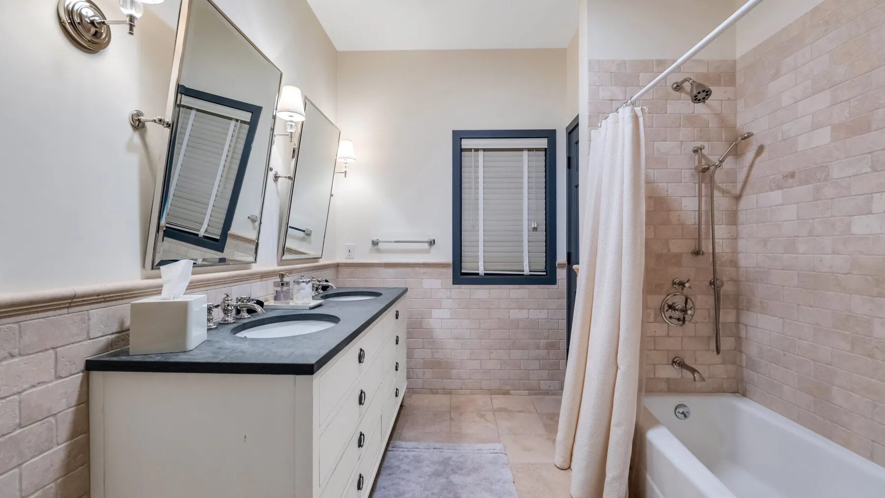 Un baño con un lavabo largo y una bañera con ducha.