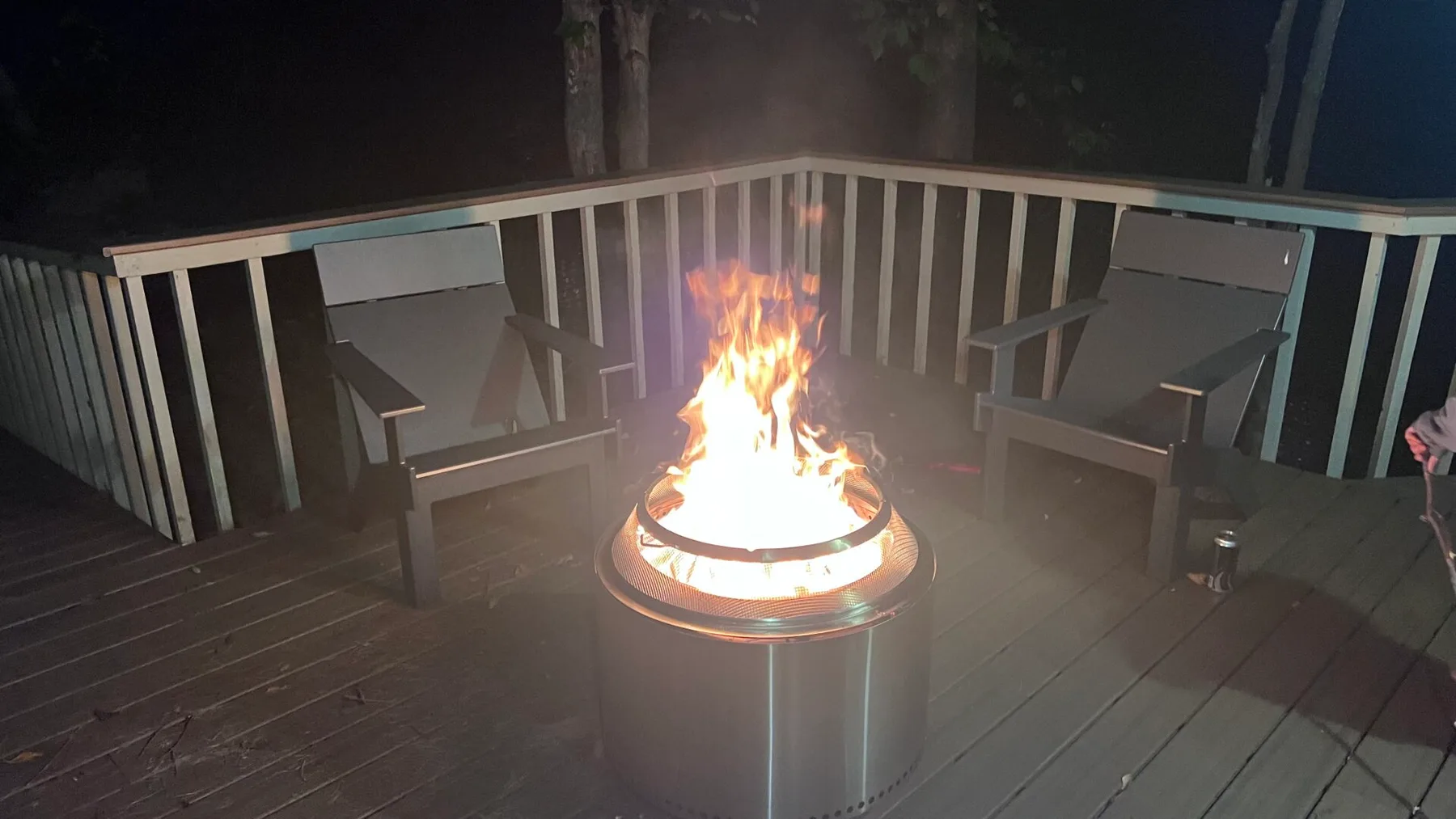 Un brasero encendido está en una terraza entre dos asientos de exterior.