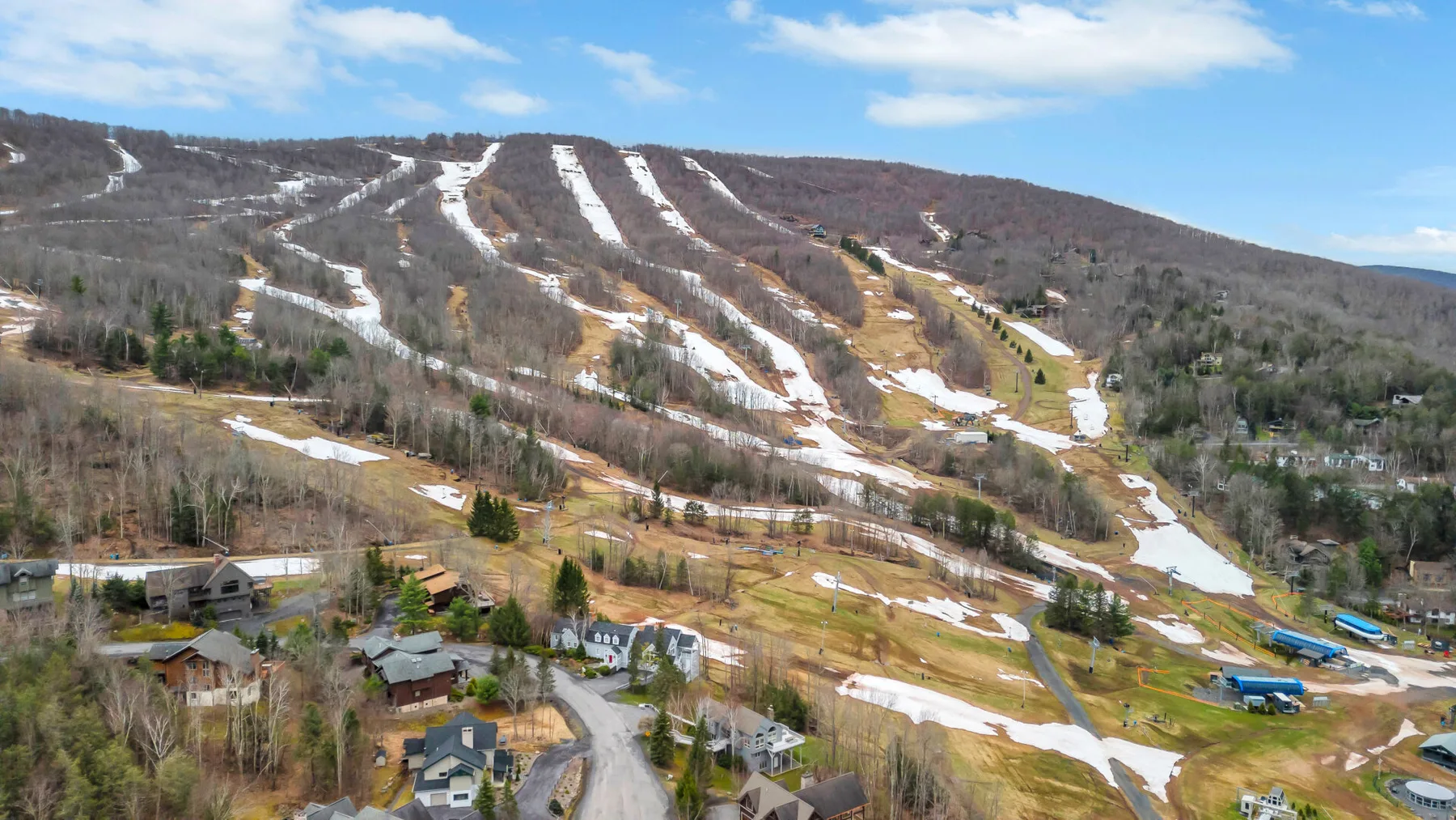 A mountain ski area with winding runs and scattered buildings.