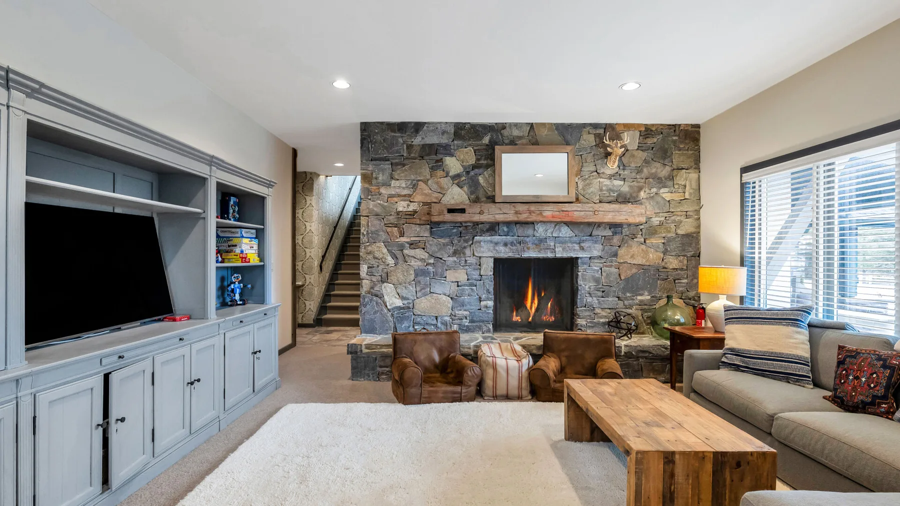 Una sala de estar con chimenea de piedra, asientos y un televisor.