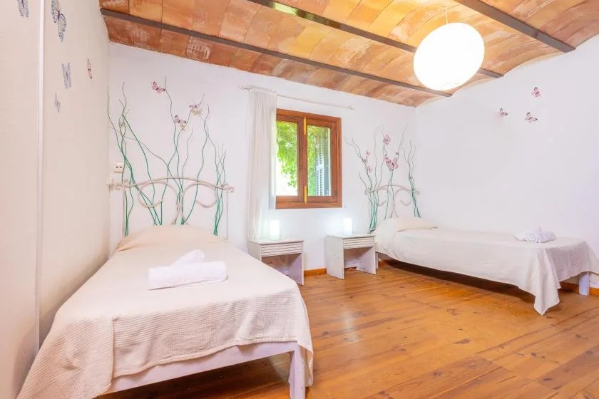 Un dormitorio con dos camas, suelo de madera y una ventana.