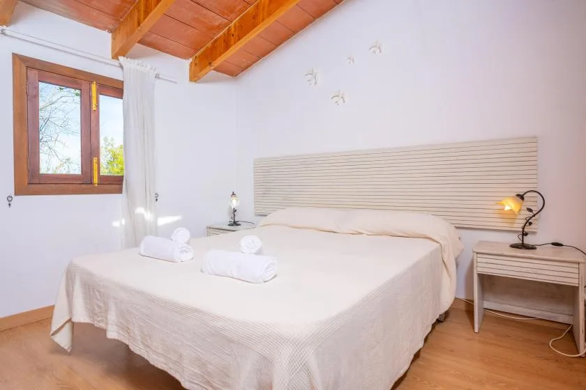 Un dormitorio con una cama, una mesita de noche y una ventana bajo un techo de madera.