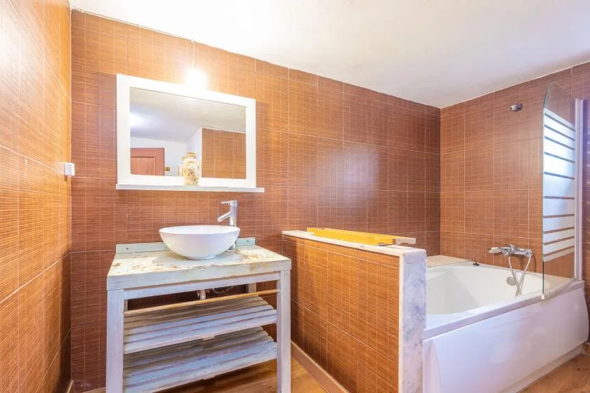Un baño alicatado con lavabo, espejo y bañera.