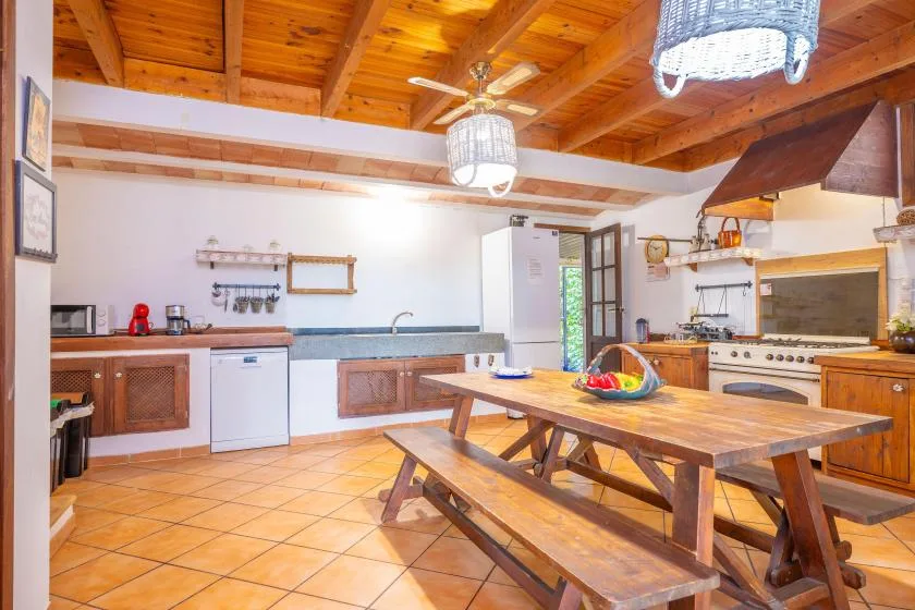 Una cocina amplia con una mesa de comedor de madera bajo vigas de madera expuestas.