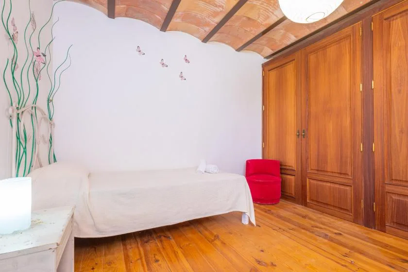 Un dormitorio con una cama, armarios de madera y un asiento rojo brillante.