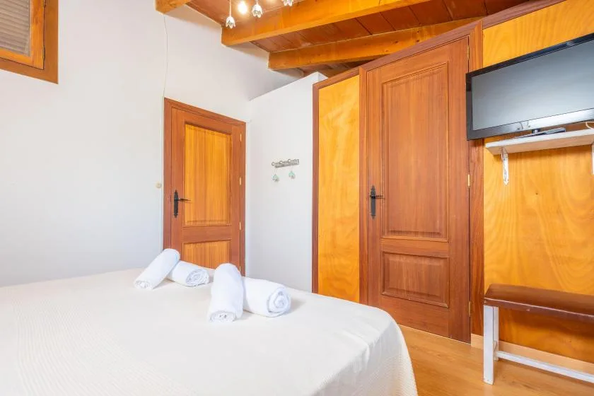 Un dormitorio con una cama bien tendida y puertas de madera.