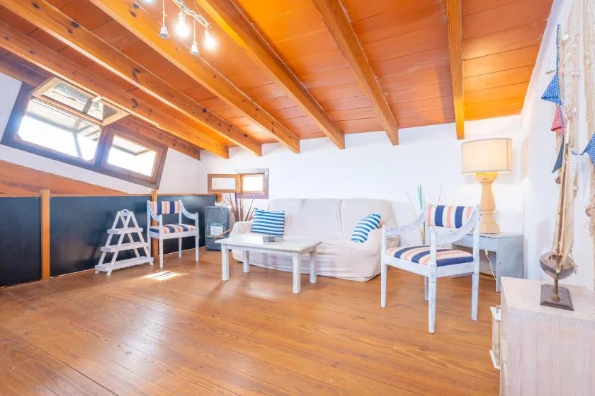 Una sala luminosa con asientos blancos y techo de madera.