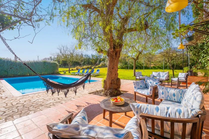 Una zona de estar al aire libre da a una piscina y un jardín.