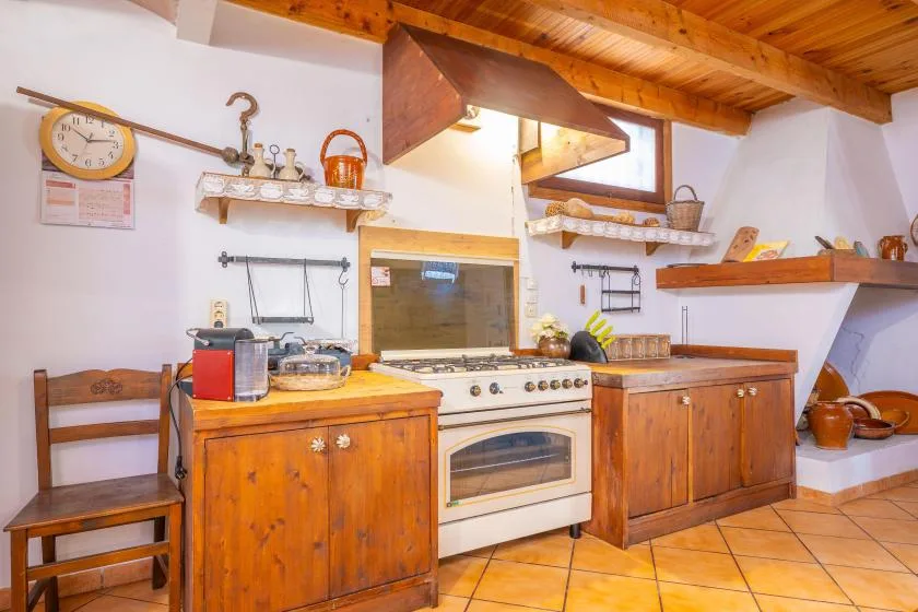Una cocina rústica con armarios de madera y una estufa bajo un techo de madera.