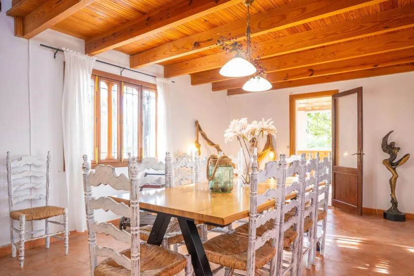 Un comedor con una mesa larga y vigas de madera en el techo.