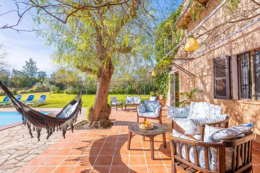 Un patio al aire libre con asientos y una hamaca junto a una piscina.