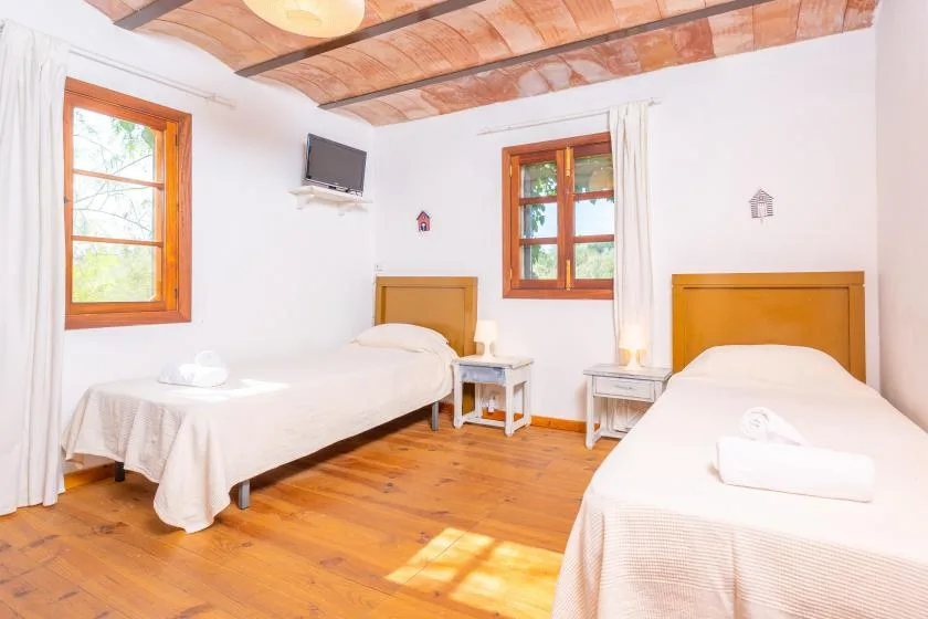 Un dormitorio con dos camas individuales y vigas de madera en el techo.