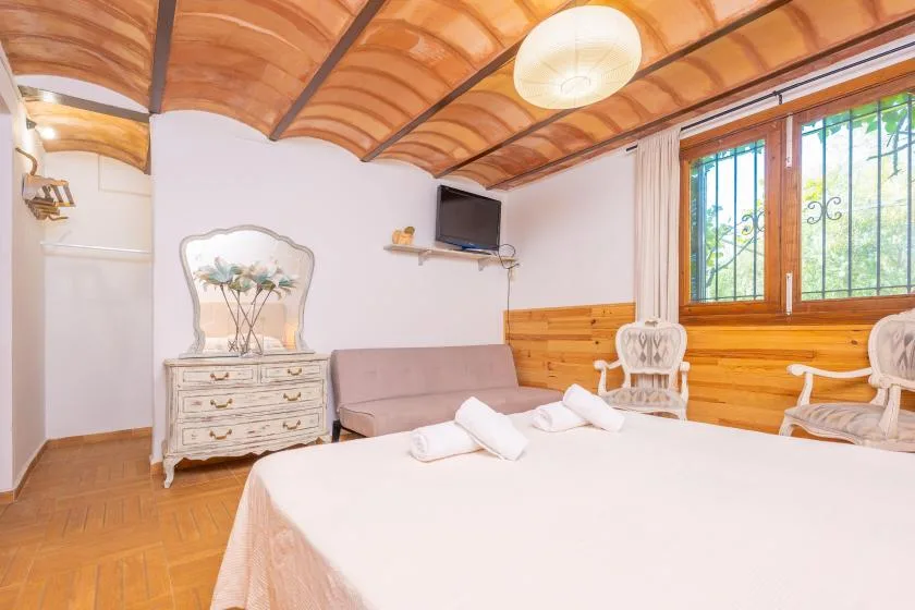 Un dormitorio con una cama grande, paredes revestidas de madera y una ventana.