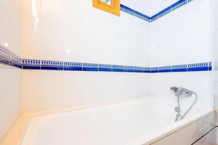 Un baño alicatado con bañera y ducha instalada en la pared.