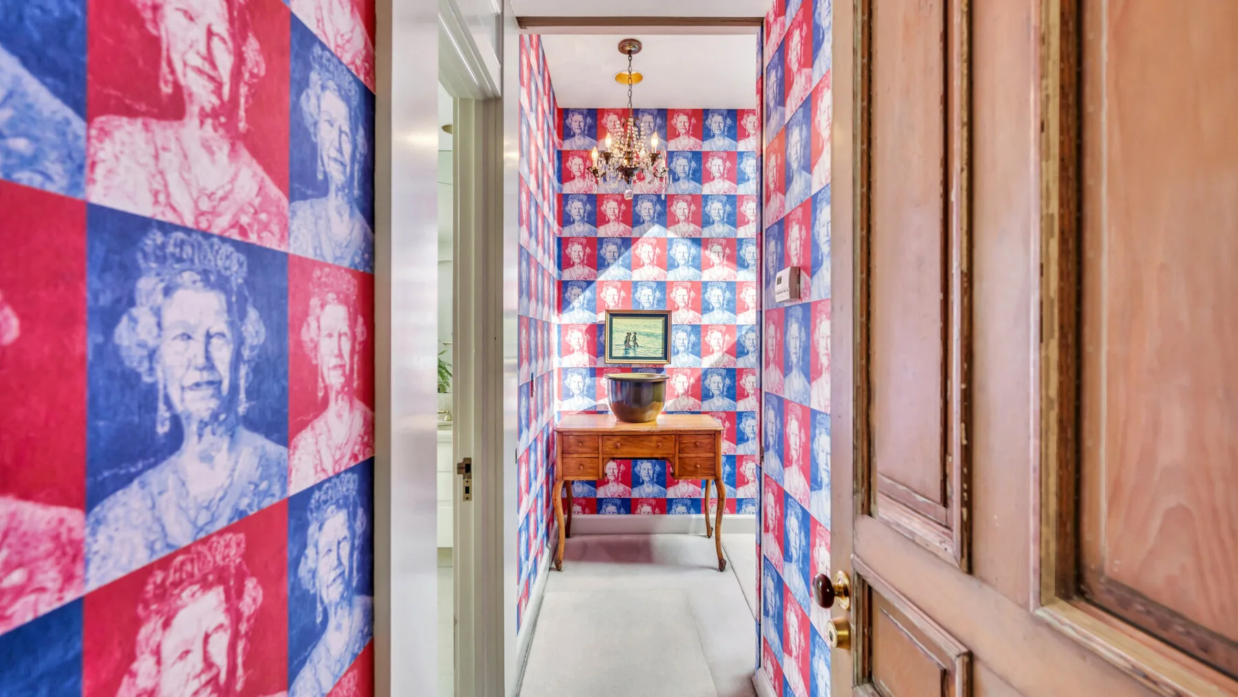 A narrow interior hallway features red and blue portrait-patterned walls.
