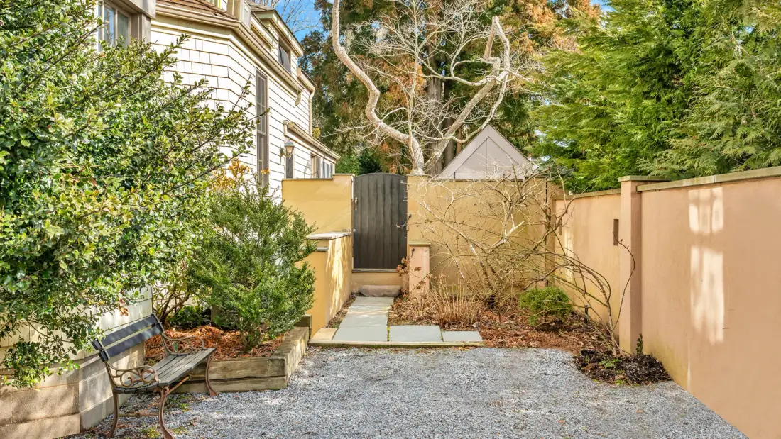 An outdoor courtyard with a gravel ground area, garden beds, and surrounding walls.