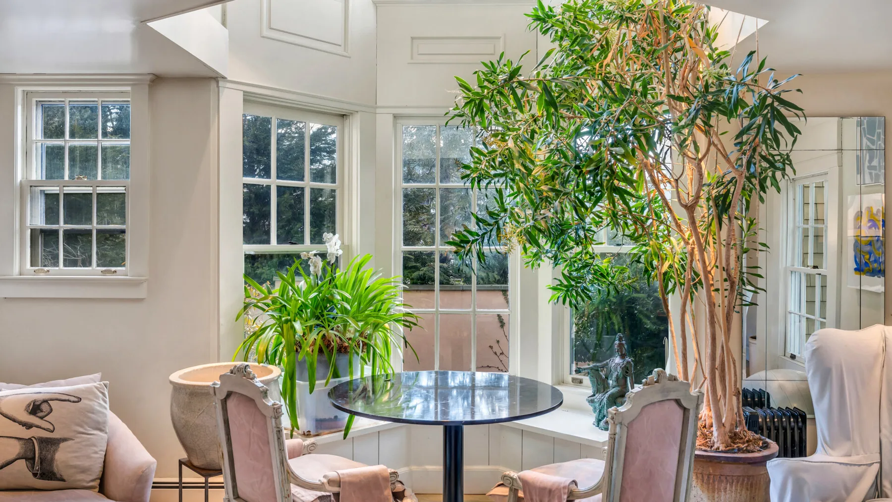 A bright sitting area with a round table, upholstered seating, and large windows.
