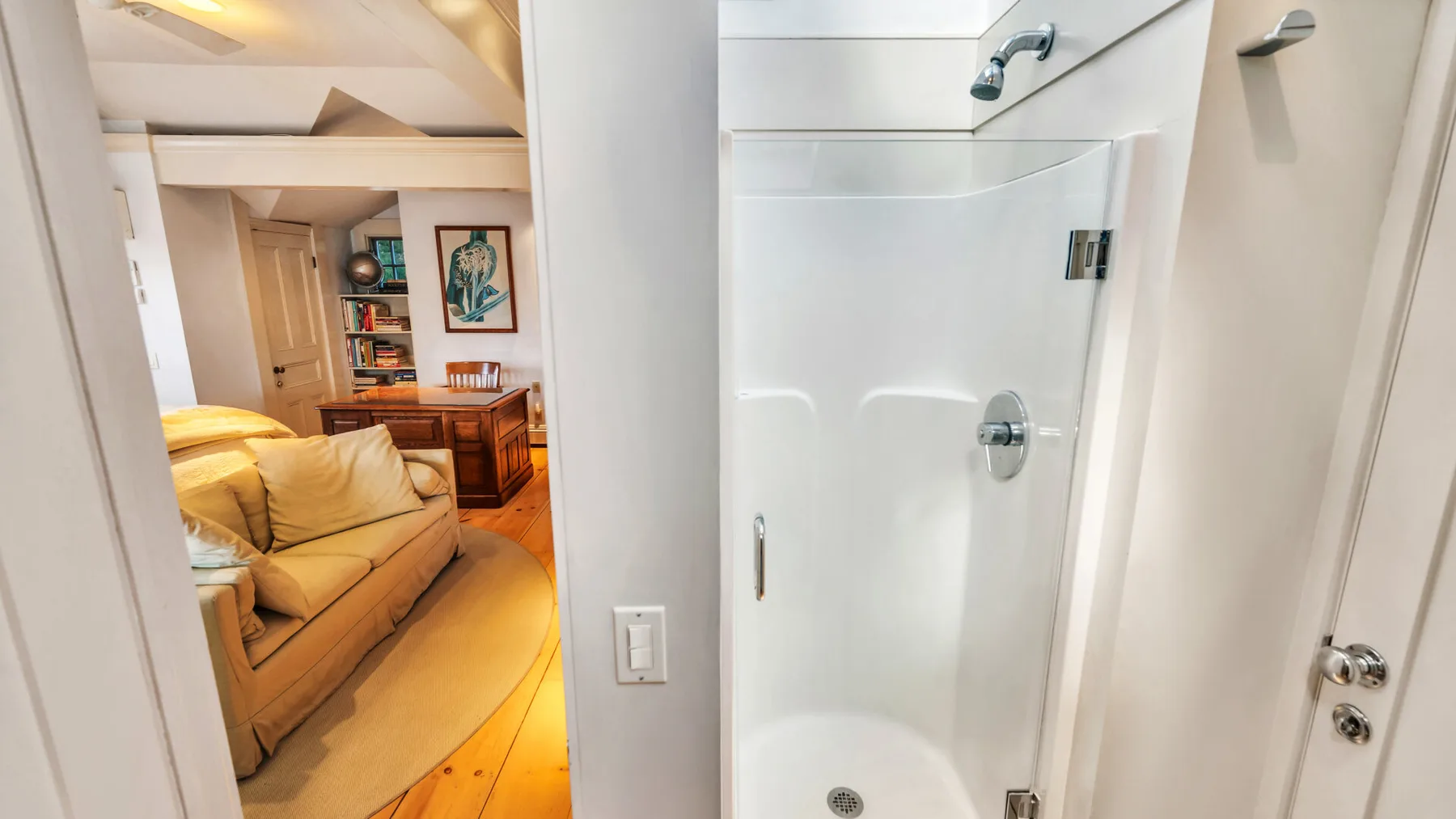 A living room with seating and a wooden table beside a bathroom shower.