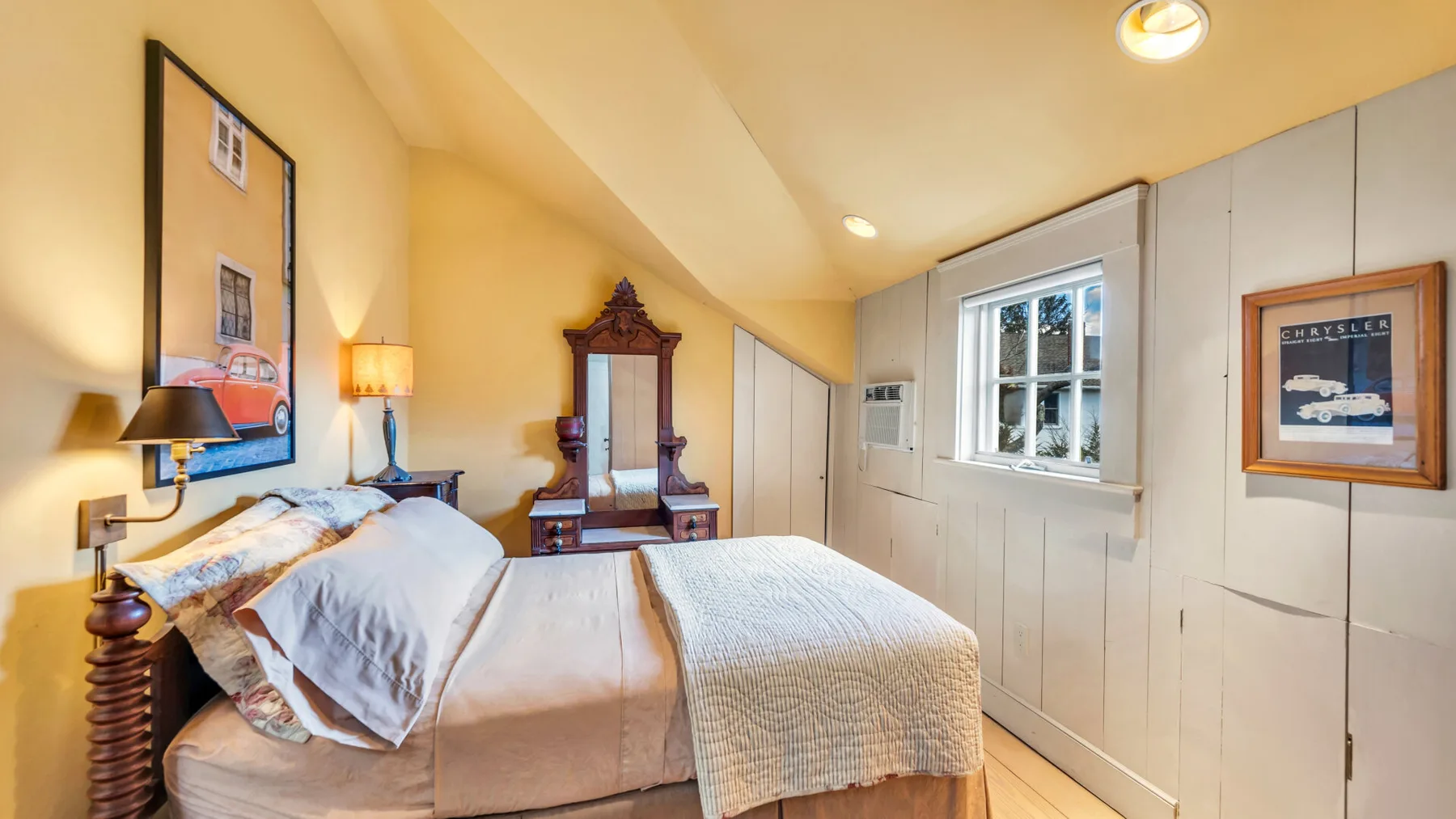 A bedroom with a bed, a window, and a wooden wardrobe.