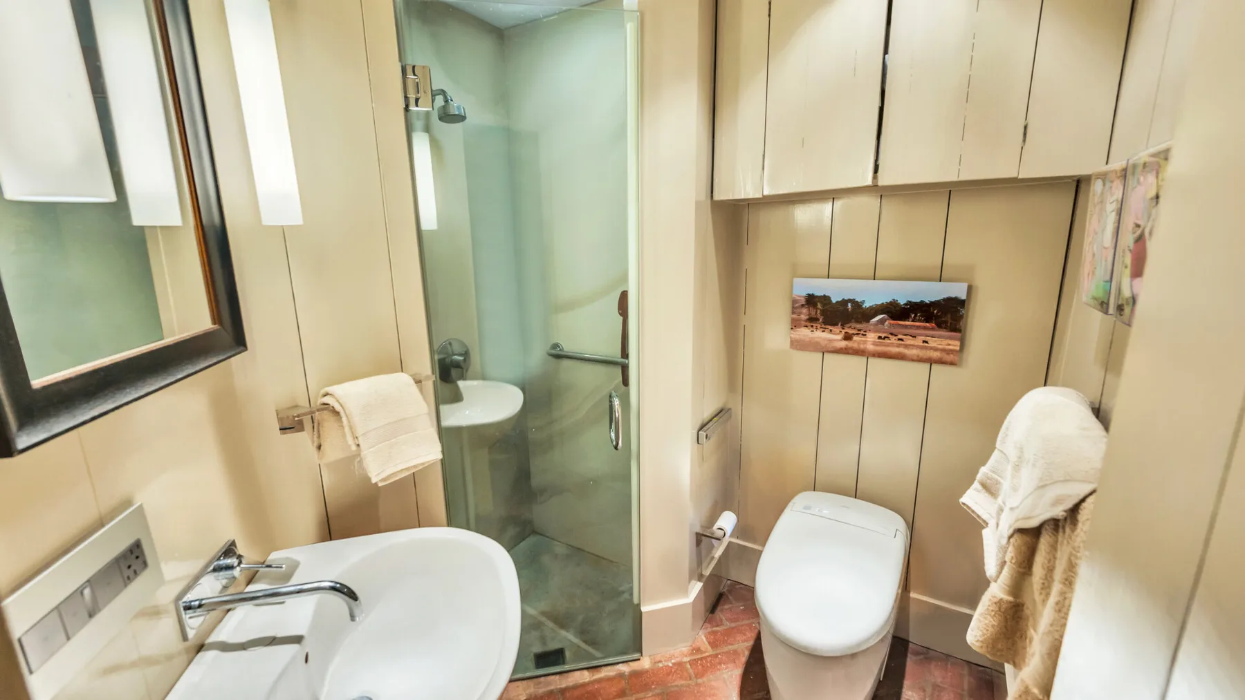 A bathroom with a sink, glass shower, and toilet.