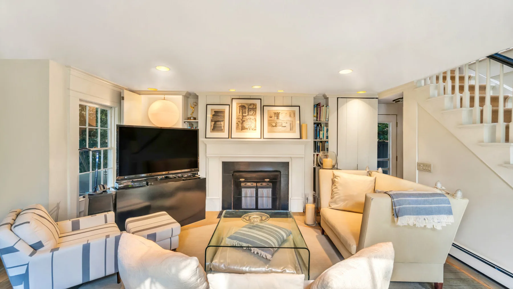 A bright living room with seating arranged around a glass coffee table and fireplace.