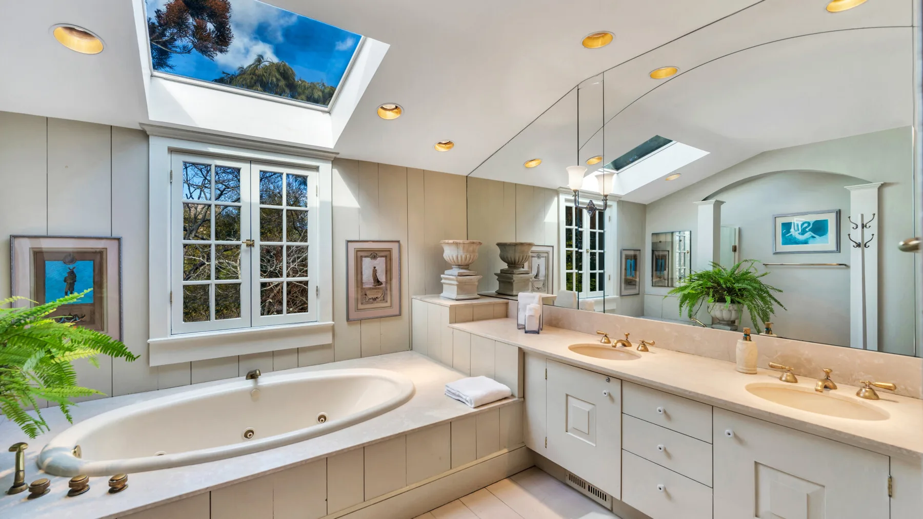 A bright bathroom with a bathtub, vanity, and large mirrors.