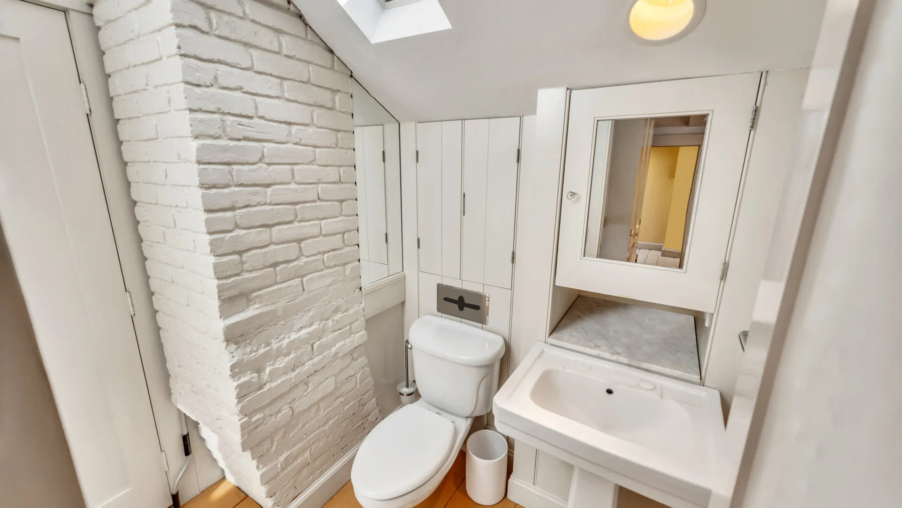 A compact bathroom with a toilet and sink beneath a mirrored cabinet.