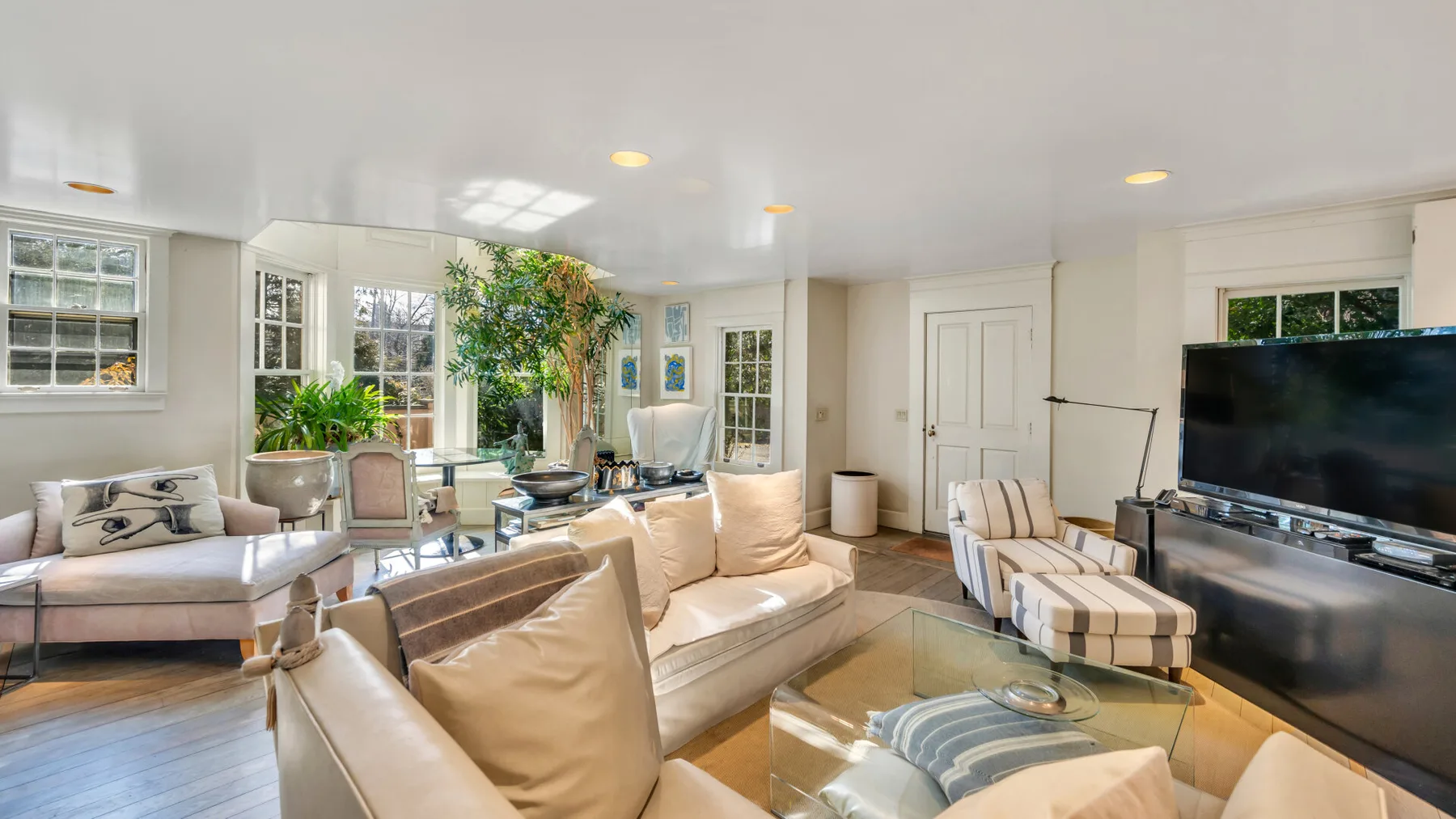 A bright living room with cream seating and a glass coffee table.