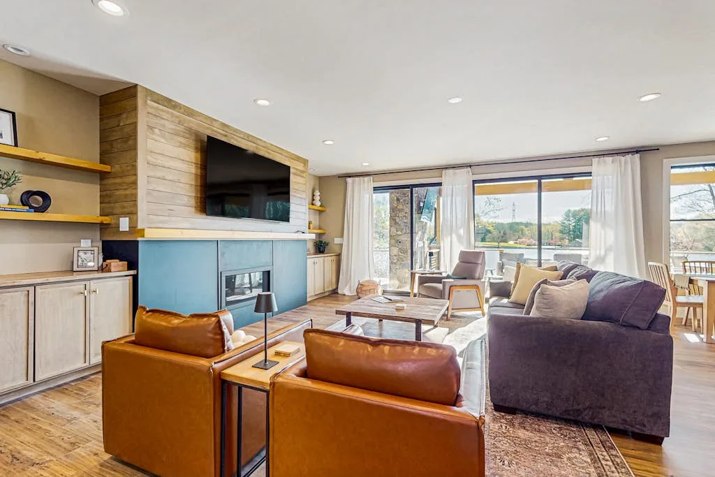 A bright living room with seating, a television, and large windows.