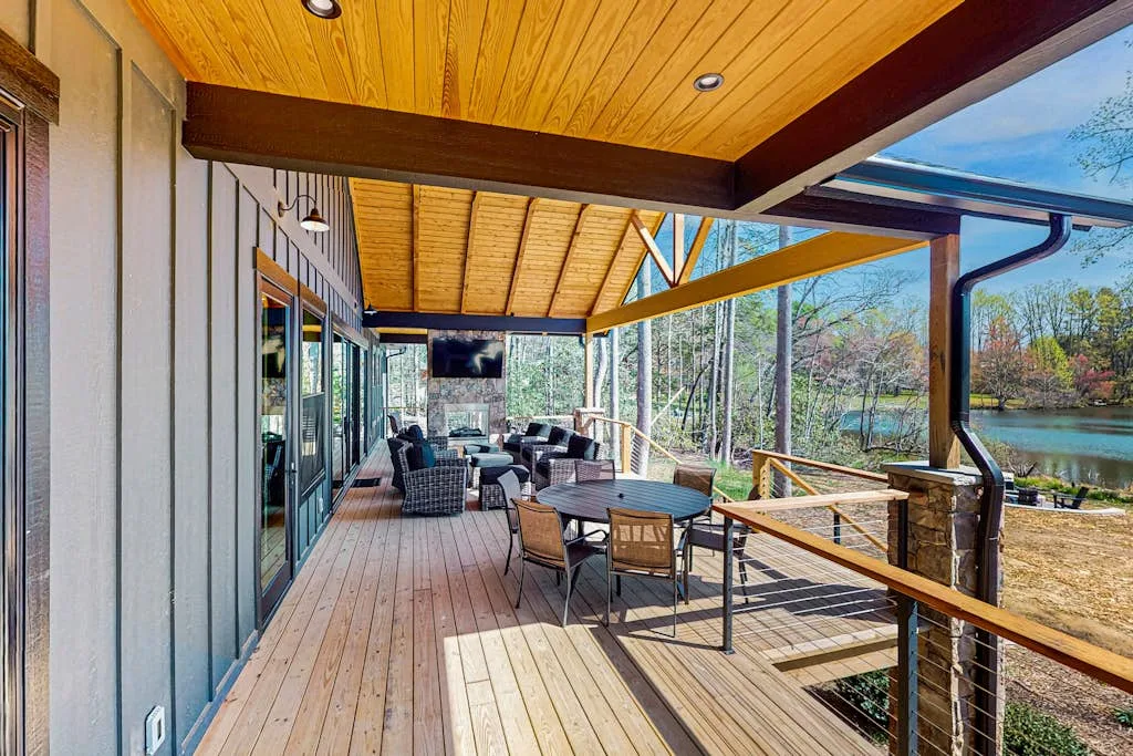 Una terraza exterior cubierta con asientos y vistas de árboles y agua.