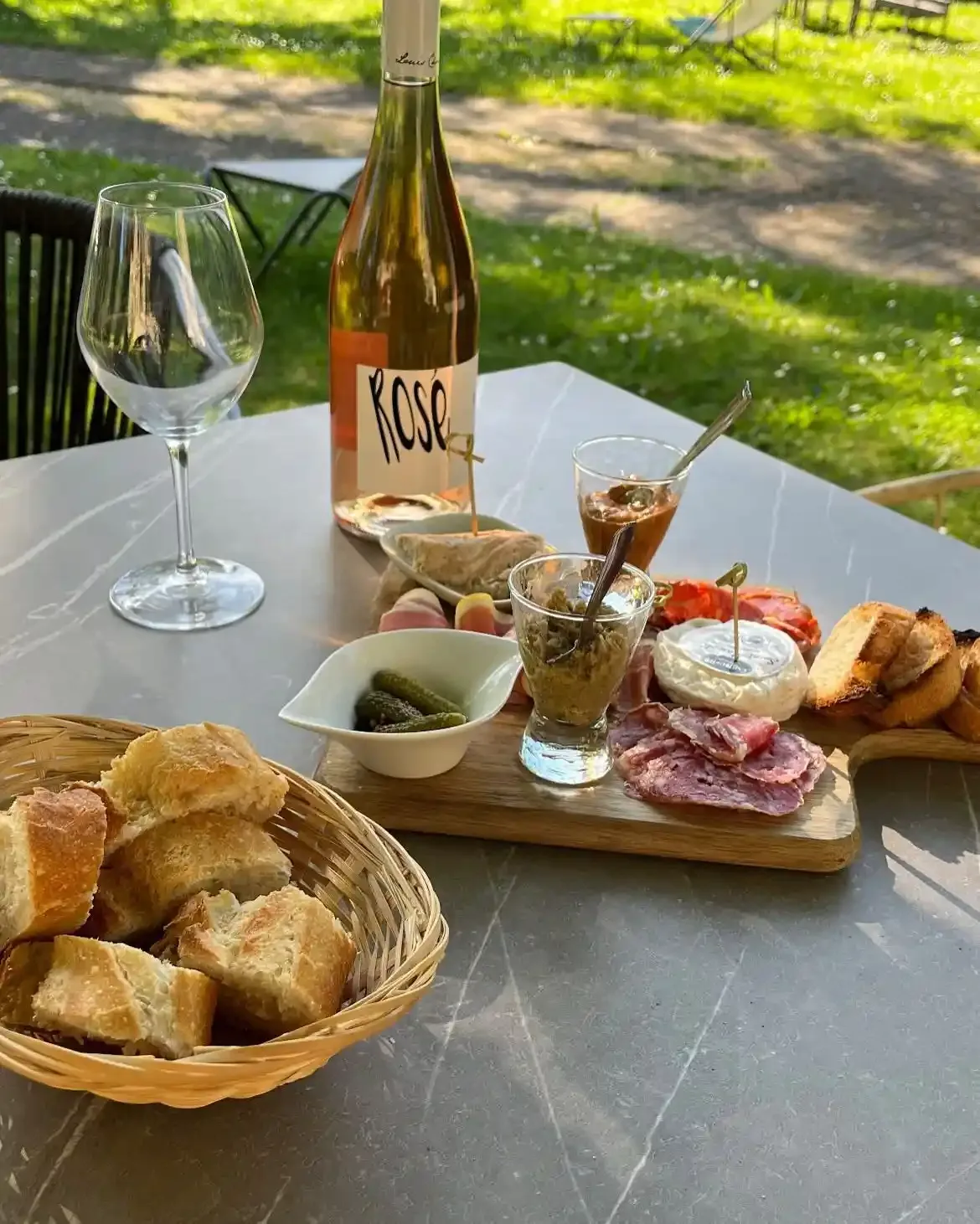 Planche de charcuterie et fromages avec pain et verre de rosé.