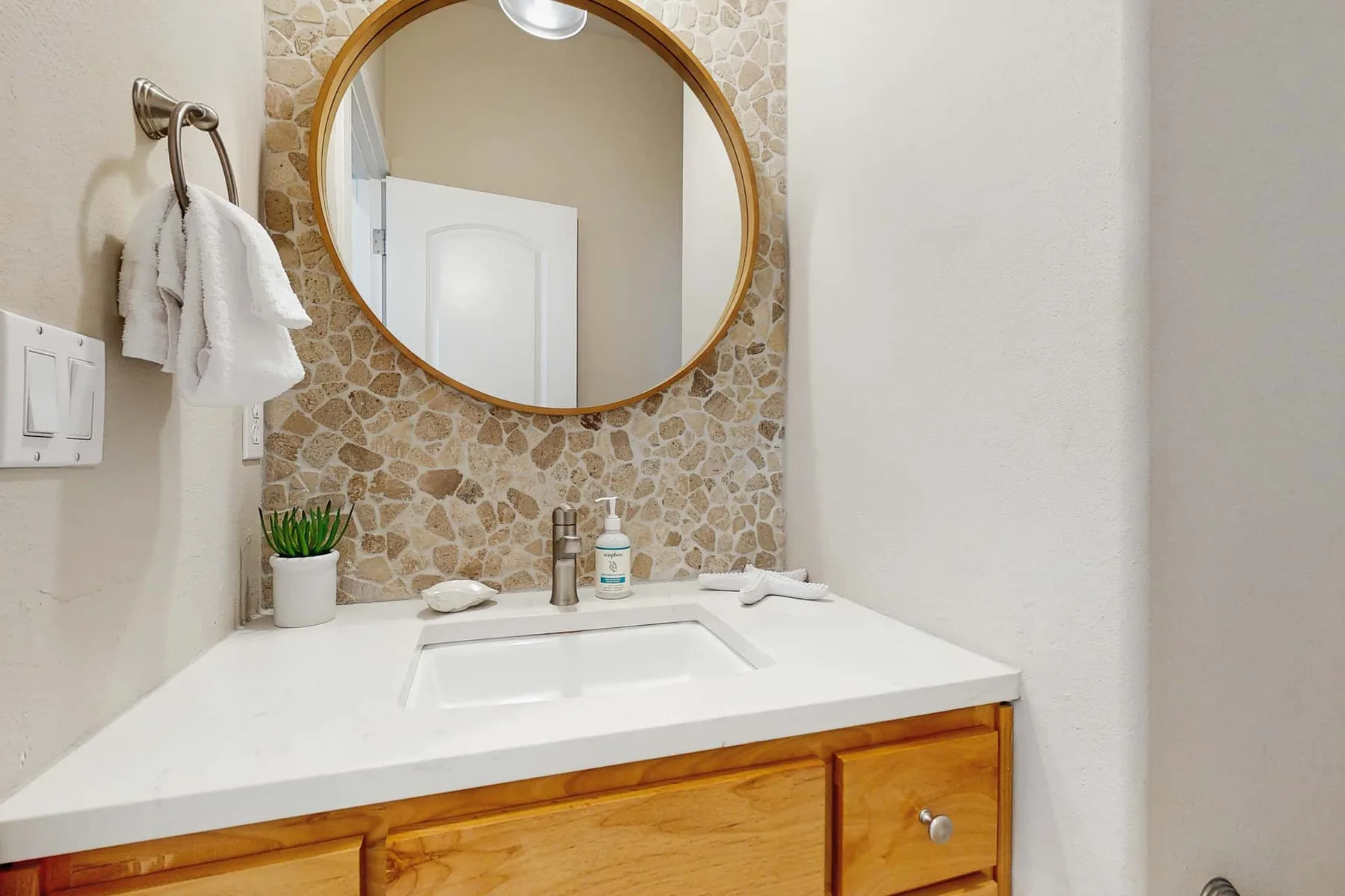 Bathroom vanity with a white sink beneath a round mirror.