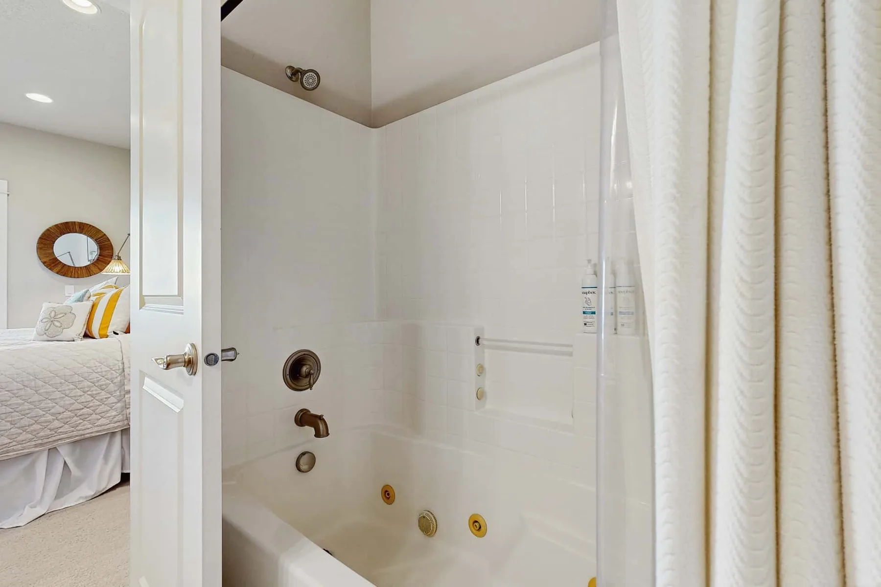 A bathroom with a bathtub and a white shower curtain beside an open doorway.