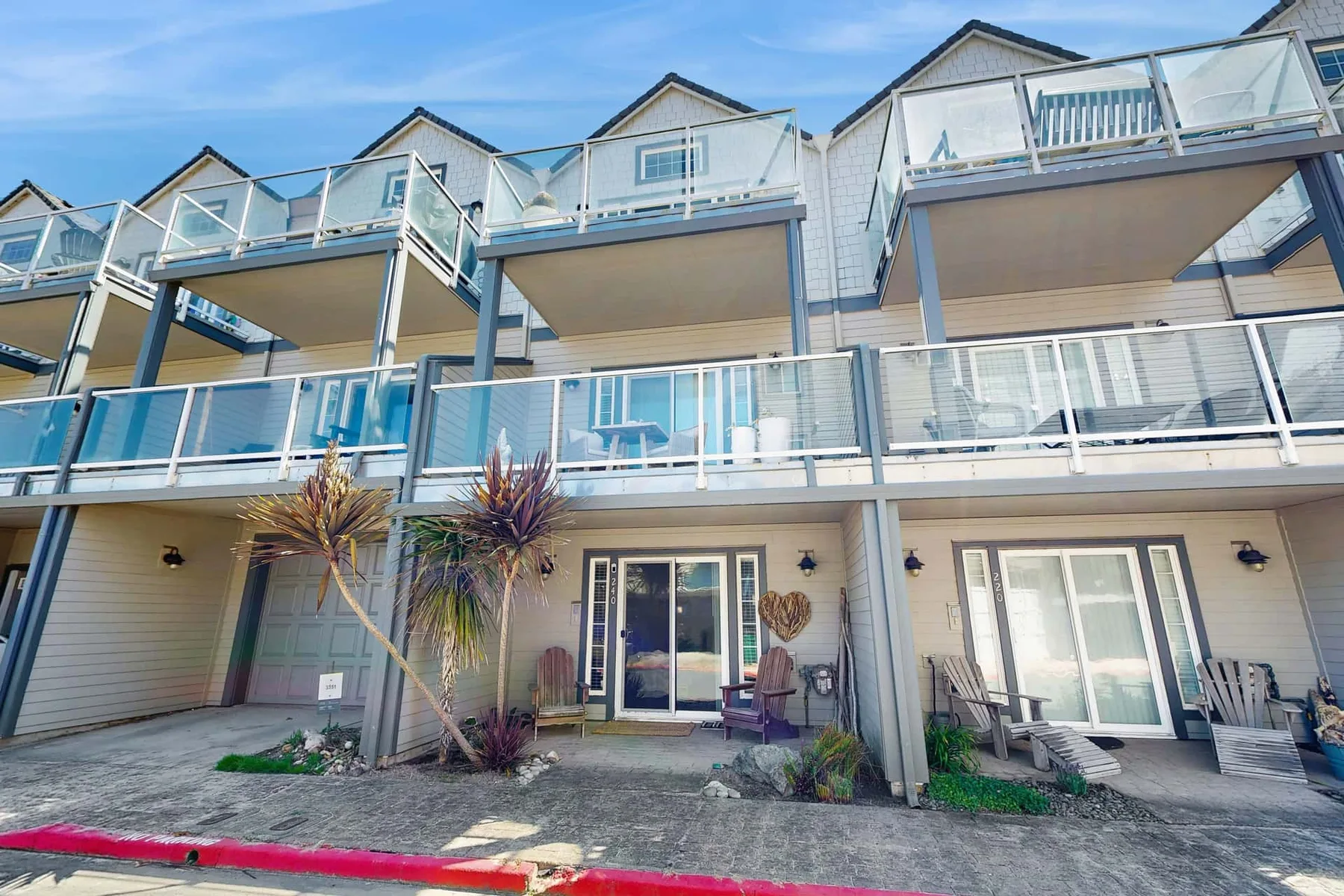 A row of coastal-style homes with balconies and ground-floor patios.