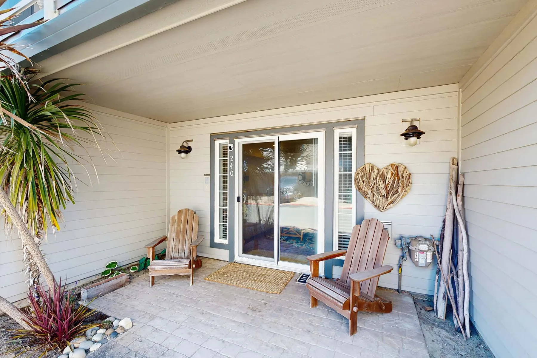 A covered patio with sliding glass doors and wooden seating.