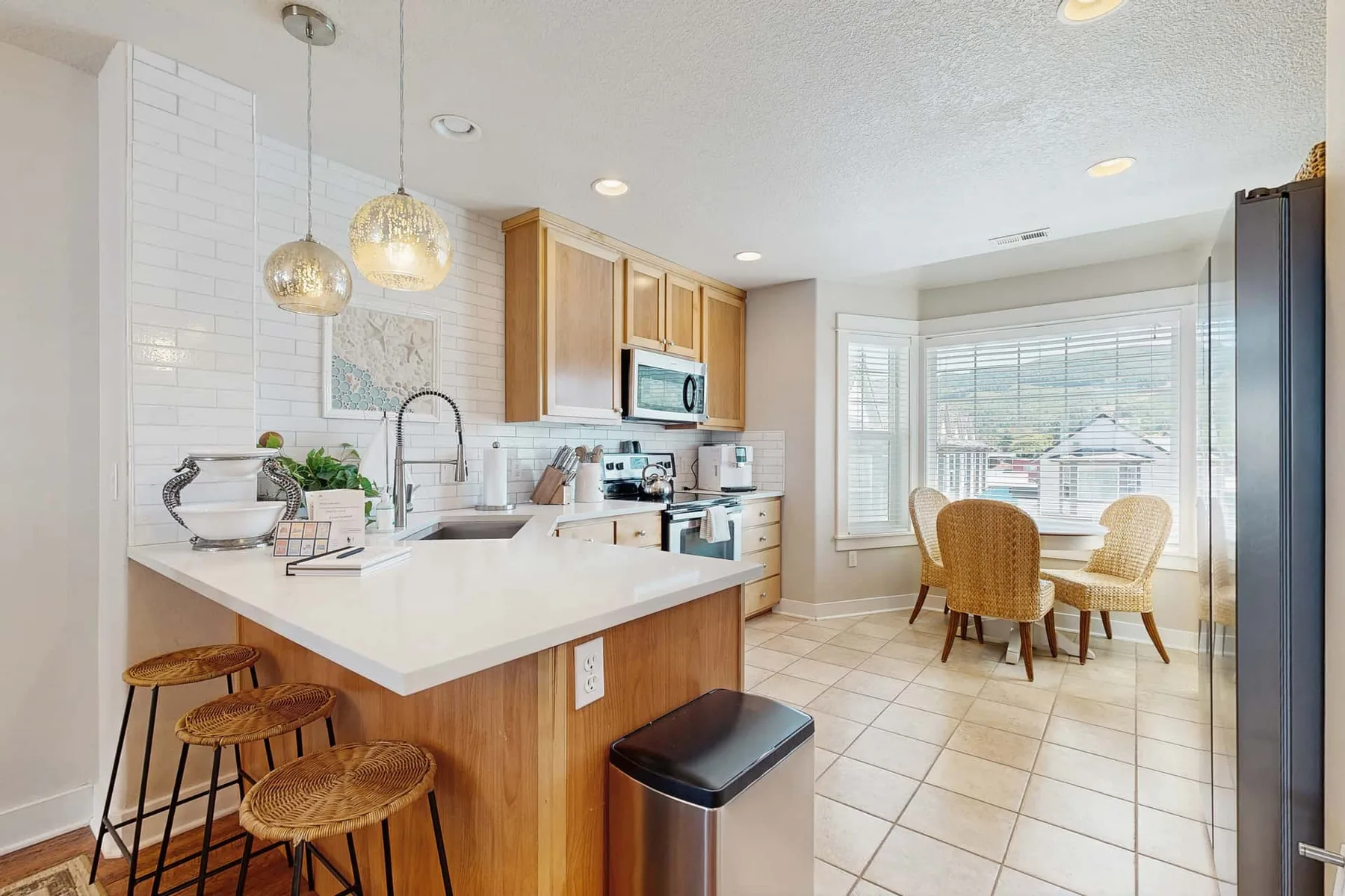 A bright kitchen with a wide island and a small dining area by the windows.