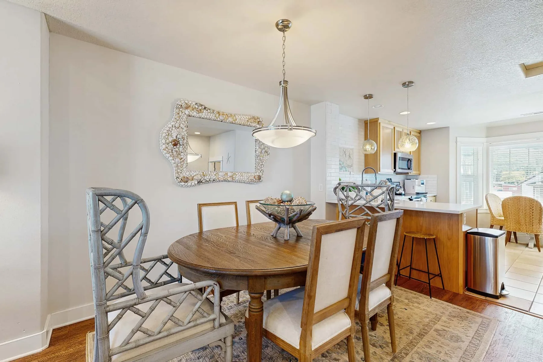 A dining area with a wooden table and chairs beside a kitchen island.