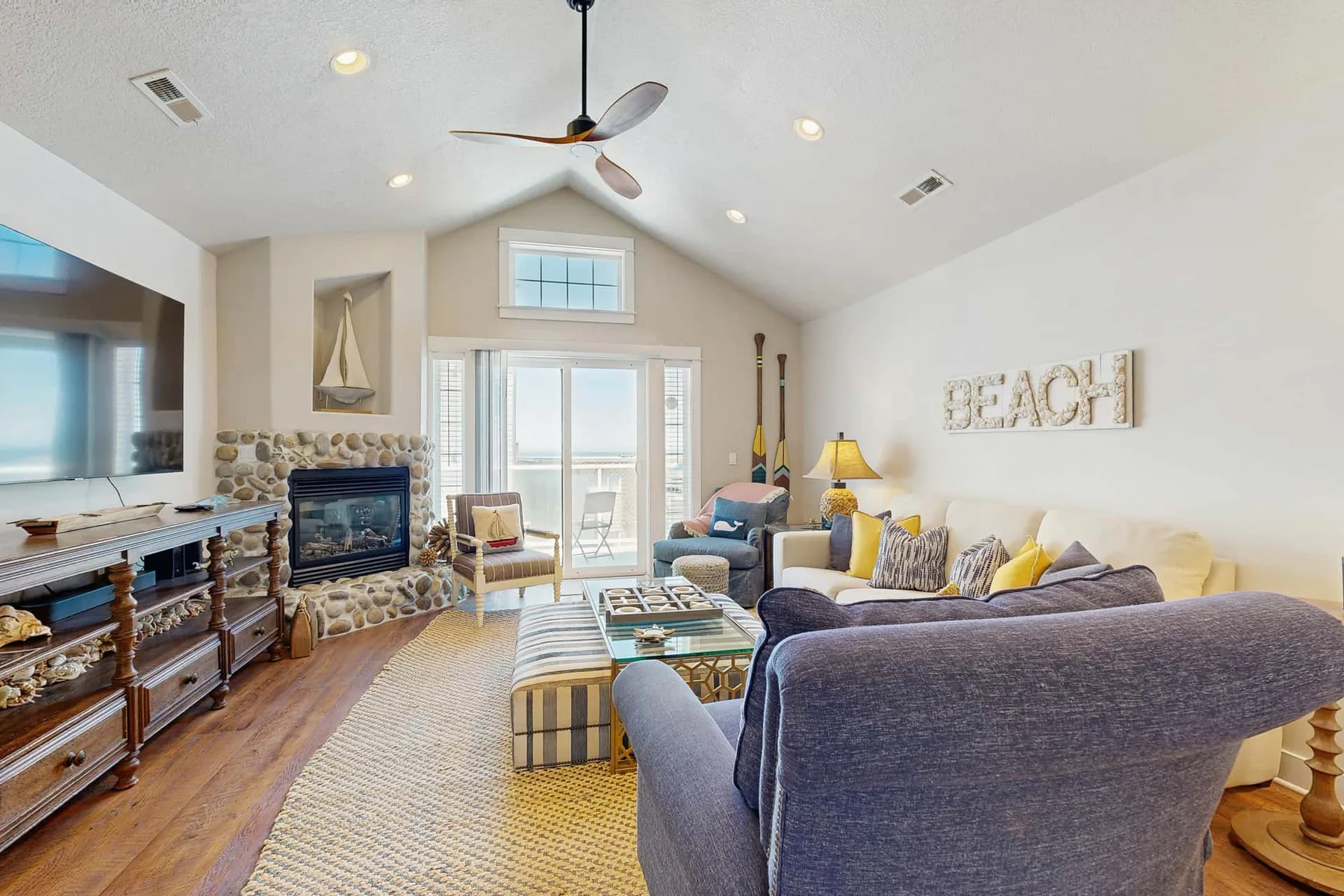 A bright living room with a stone fireplace and seating around a coffee table.