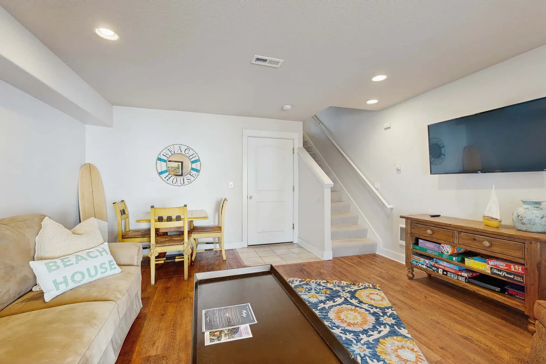 A living room with seating, a dining table, and stairs along the wall.