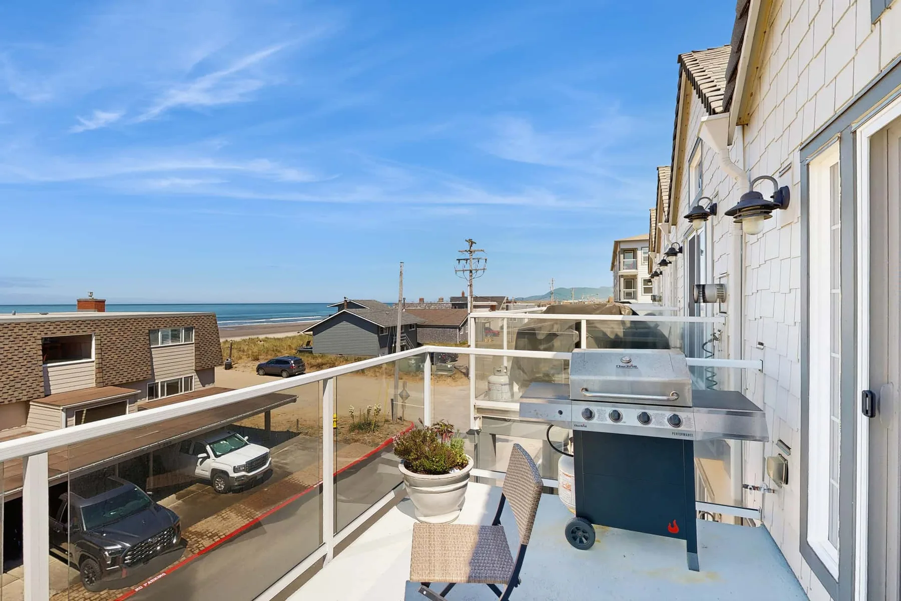 A seaside balcony with a barbecue grill and views of the ocean.
