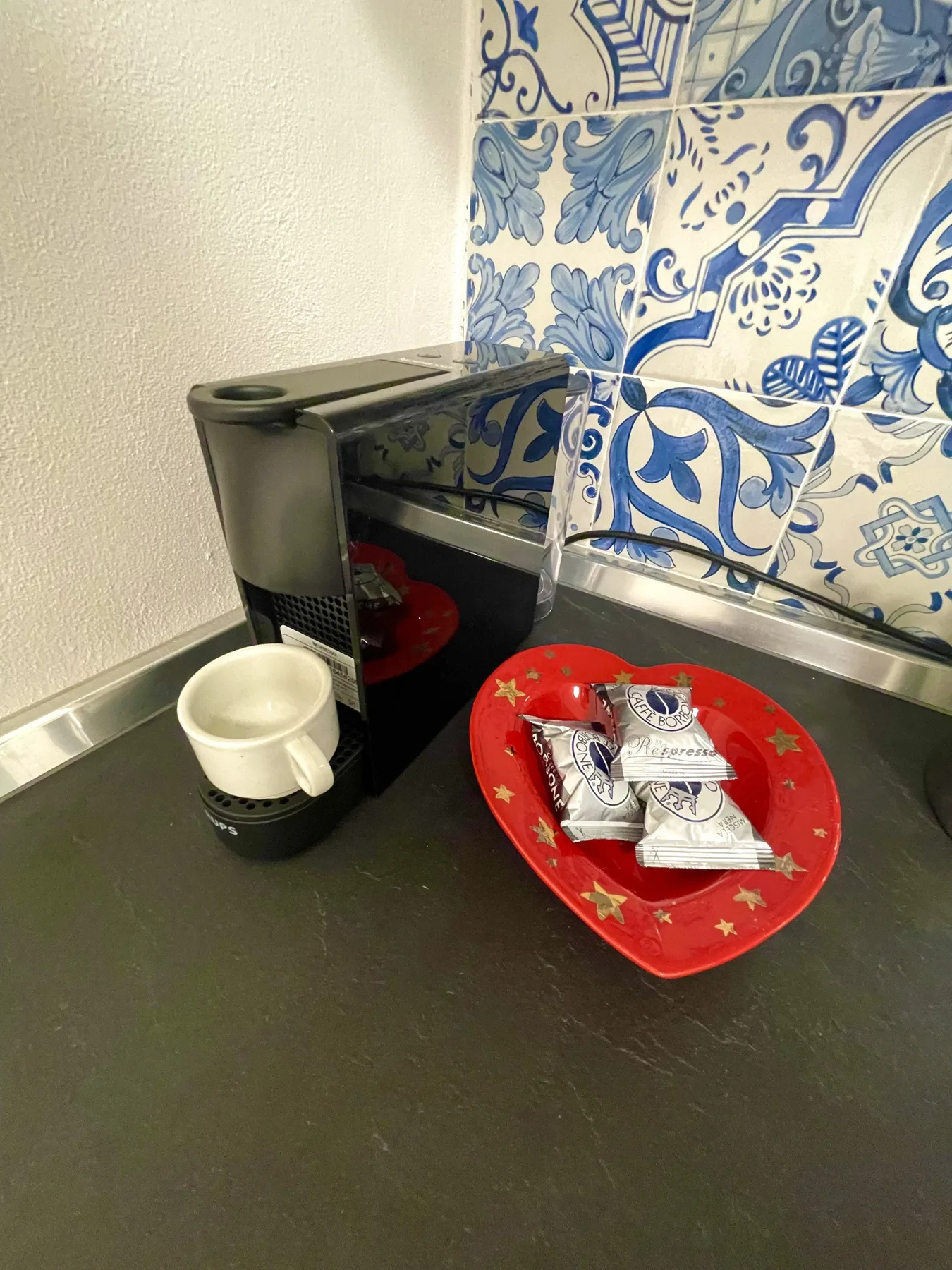 A coffee machine and cup sit beside a red tray on a kitchen counter.