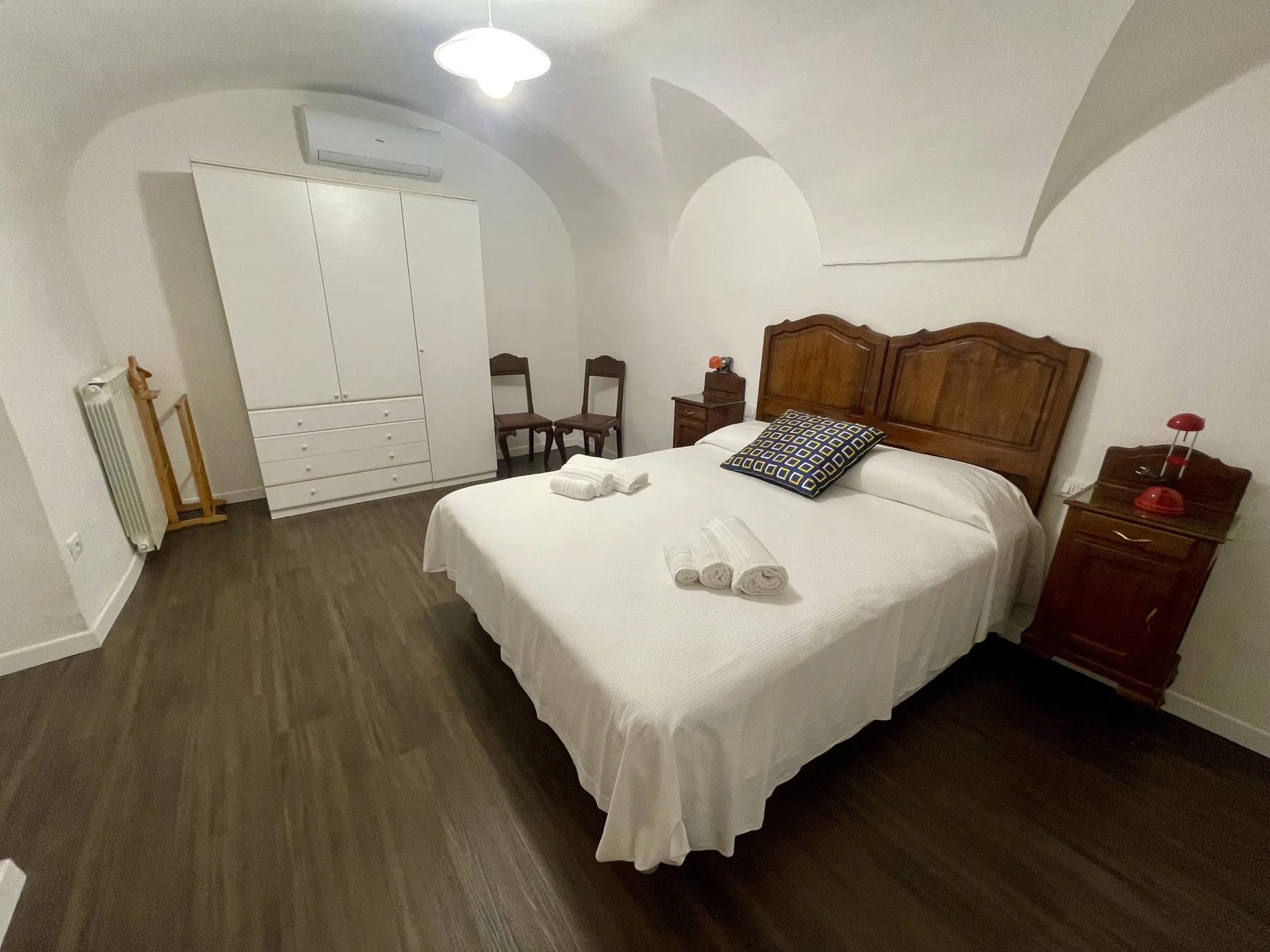 A bedroom with a large bed, white bedding, and wooden bedside tables.
