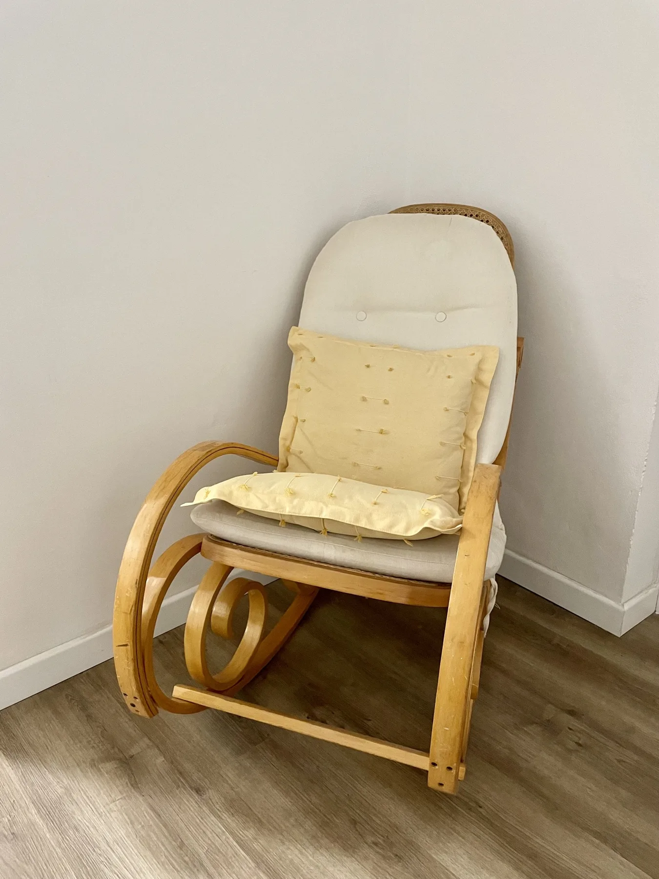A cushioned rocking chair with pale yellow pillows sits in a corner.
