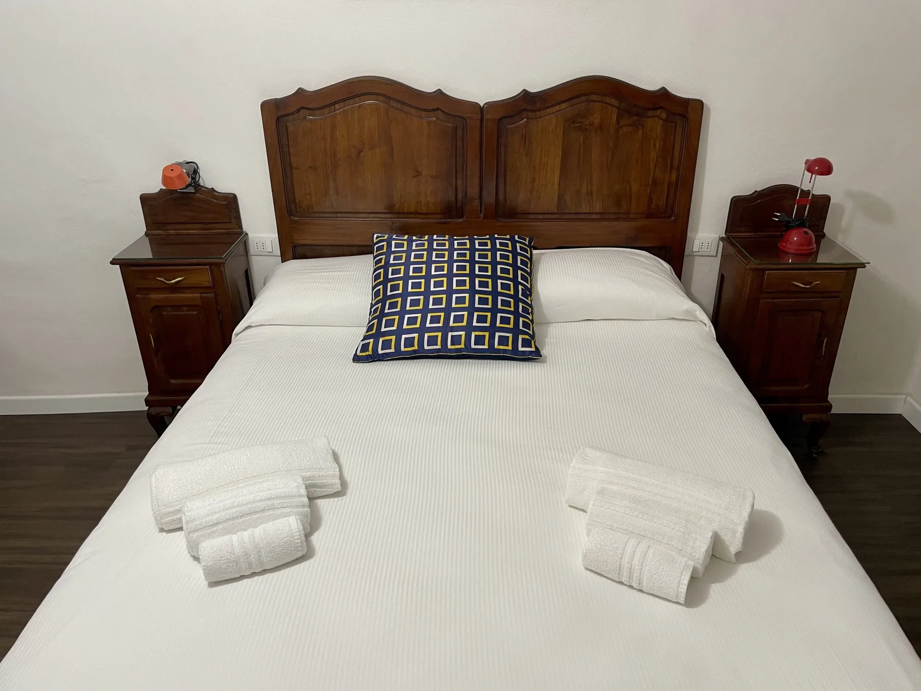 A bedroom with a neatly made bed and matching wooden bedside tables.