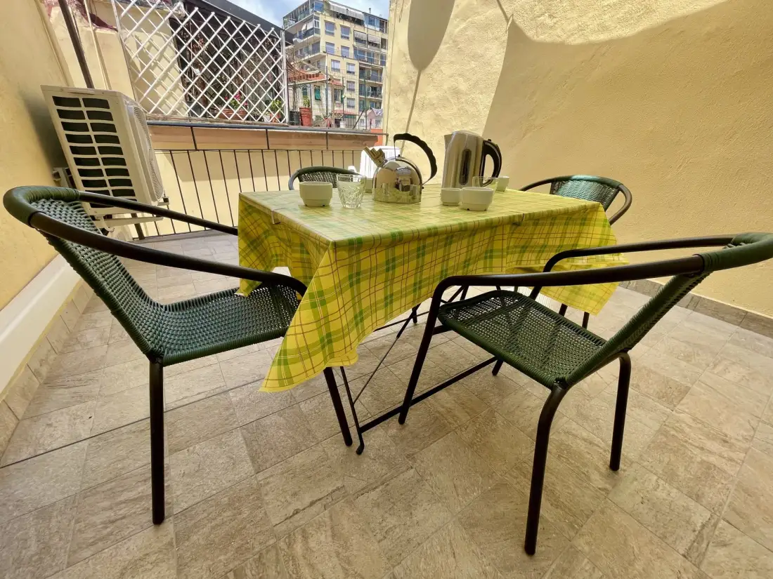 A small outdoor seating area with a table, chairs, and a yellow checkered tablecloth.
