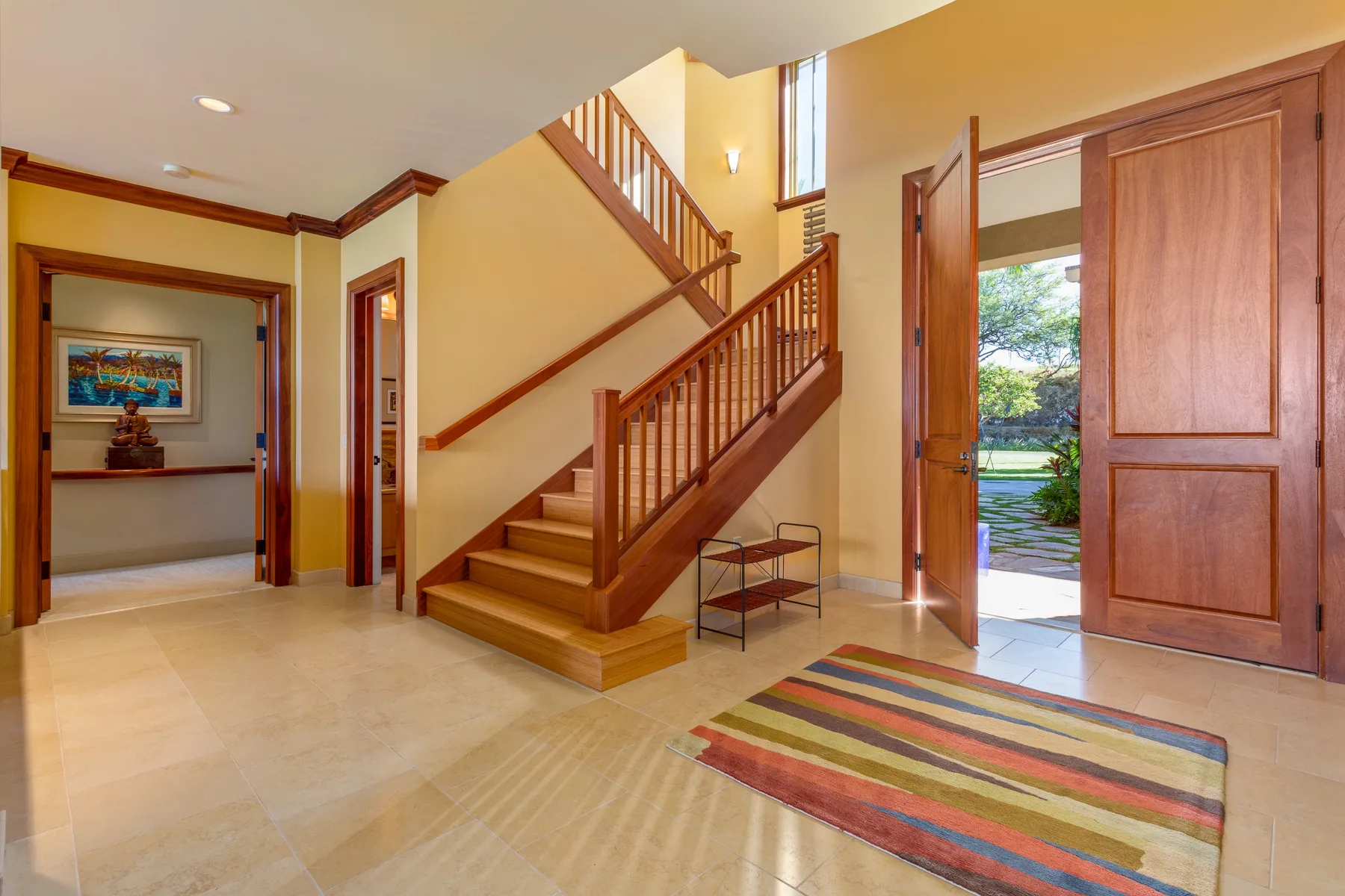A spacious entry hall with a wooden staircase and an open exterior door.