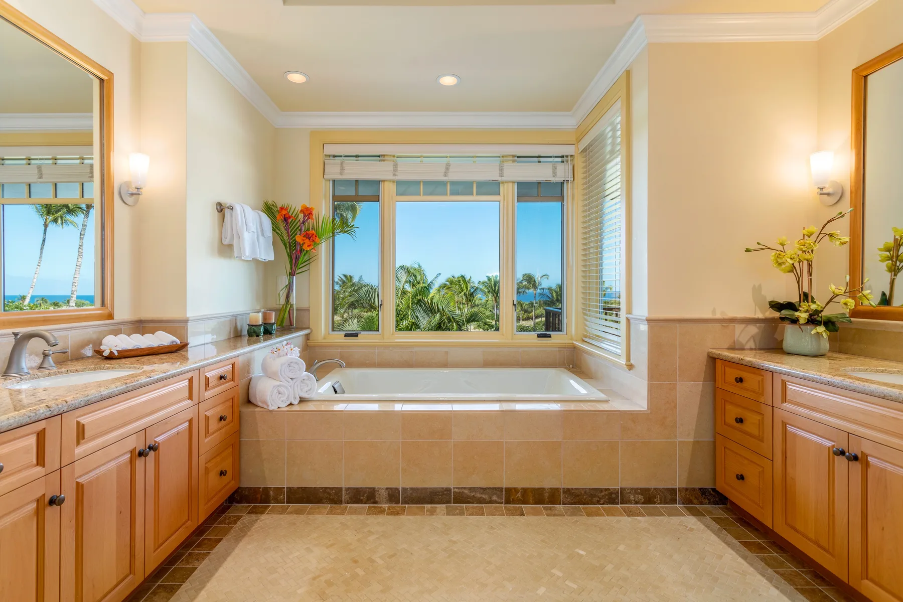 A bright bathroom features a large bathtub beneath a wide window.